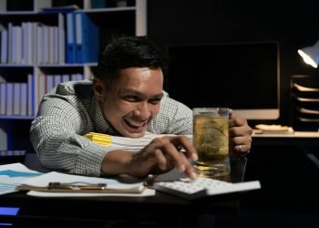 asian-man-working-overtime-drinking-beer-while-using-calculator-in-office-at-night-.jpg